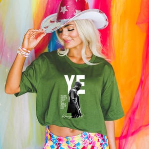 May include: Green t-shirt with the word "YE" in white block letters and a black and white image of a man. The shirt also features the text "Telling truth is crazy in a world full of lies" and the name "Kanye West". A sequined cowboy hat with stars.