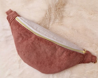 Könnte beinhalten: Eine braune Cord-Bauchtasche mit einem weißen Reißverschluss und goldenen Beschlägen.