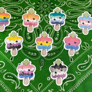 May include: Nine colorful star-shaped stickers with a dripping ice cream design. Each sticker features a different pride flag, including the transgender, lesbian, gay, bisexual, pansexual, asexual, genderfluid, non-binary, and intersex flags.