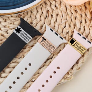 May include: Three silicone watch straps in black, white, and pink, each with a metal accent. The straps feature medical alert text, including "AFB/WARFARIN, NONSADS" and "EPILEPSY ON KEPRRA." The straps are designed for Apple watches.