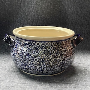 May include: A large blue and white ceramic crock with a lid. The crock is decorated with a floral pattern and has two handles.