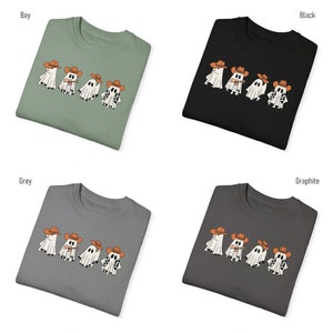 May include: Four white ghosts wearing cowboy hats and playing musical instruments. The ghosts are printed on a t-shirt in various colors: bay, black, grey, and graphite.