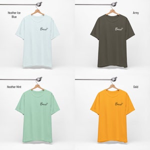 May include: Four t-shirts hanging on hangers, each in a different color: heather ice blue, army, heather mint, and gold. Each shirt has the word "Barre" printed on the front in black cursive.