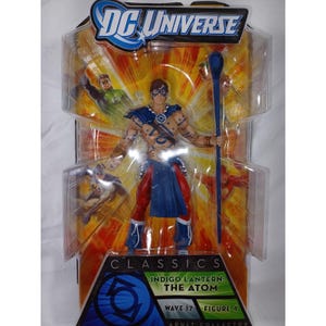 May include: A DC Universe Classics action figure of Indigo Lantern: The Atom, packaged in a clear plastic blister pack. The figure is a male character with a blue and red costume, holding a blue staff. The packaging features the DC Universe logo and images of other characters.