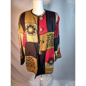 May include: A patchwork jacket in shades of black, red, tan, and gold. The jacket features a round neckline, long sleeves, and decorative buttons. The design includes floral and abstract patterns.