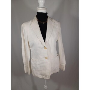 May include: Off-white blazer with two buttons and two front pockets. The blazer is displayed on a white mannequin. The blazer has a classic design and is made of a light-colored fabric. The blazer is a versatile piece of clothing.