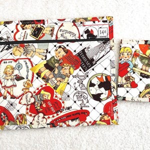 Può includere: Un set di tessuto bianco con una grande pochette con cerniera e un portafoglio più piccolo, entrambi decorati con un tema vintage di San Valentino. Il design include cuori rossi, bambini e grafiche di francobolli. La pochette ha una cerniera nera.