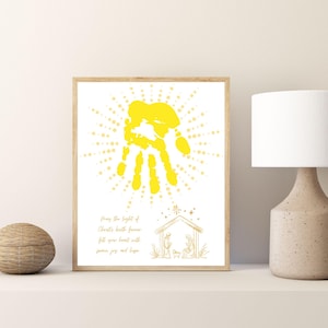 May include: A yellow handprint with a starburst effect, surrounded by a white border. The text reads "May the light of Christ's birth forever fill your heart with peace joy and hope". A simple line drawing of the nativity scene is at the bottom.