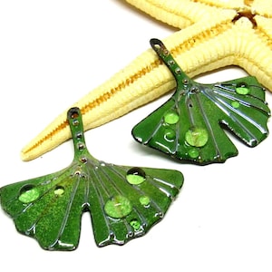 May include: Two green ginkgo leaf charms with a textured surface and raised green dots. The charms have a hole at the top for hanging.