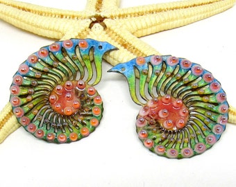 May include: A pair of colorful enamel earrings shaped like nautilus shells. The earrings are decorated with a swirling pattern of blue, green, and orange enamel, and have a raised, textured surface. The earrings are accented with small, round, red beads.