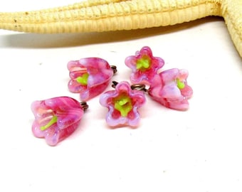 May include: Five pink glass flower charms with green centers. The charms have a swirl pattern and are attached to a silver jump ring.