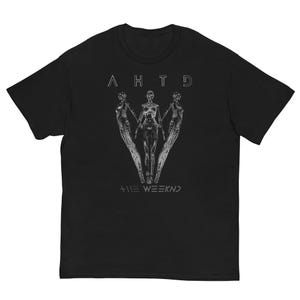 May include: Black t-shirt featuring a graphic design with the text "AHTD" above three stylized figures and "+ THE WEEKND" below. The design is in a silver color, creating a contrast against the black fabric.