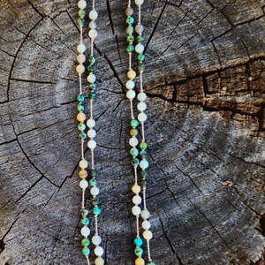 May include: A double-strand necklace with green, white, and brown beads. The necklace is made of natural stones and has a gold clasp.