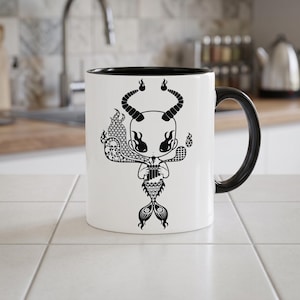 May include: A white ceramic mug with a black interior and handle, featuring a black graphic illustration of a horned, mermaid-like creature playing a pan flute, surrounded by flames and small skull patterns on the front surface.