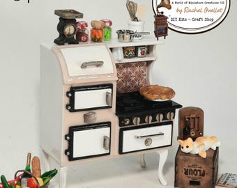 May include: A miniature DIY kit of a vintage-style stove and oven, painted in white and pink, with black accents. The stove has a pie on the stovetop, and a basket of food. The text "Stove - Oven" and "DIY Kit" are visible.