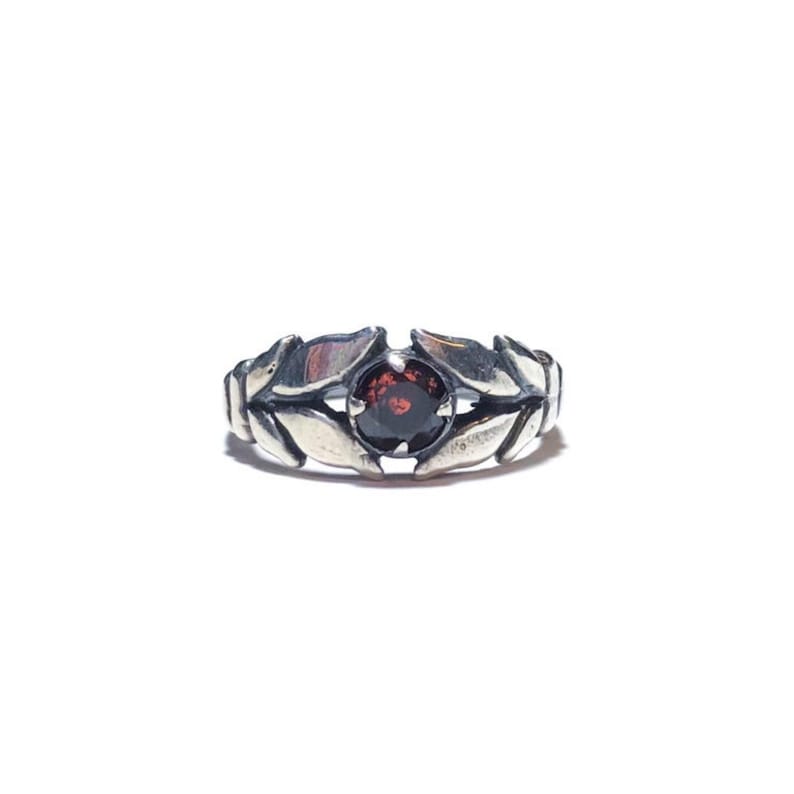 May include: A silver ring featuring a dark red gemstone set within a leaf design.