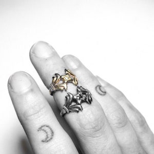 May include: Two silver rings with floral designs. The top ring has a gold flower with a small diamond in the centre.