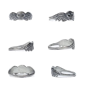 May include: A silver ring with a skull and wings design. The ring is shown from multiple angles.