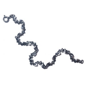 May include: A silver bracelet with a repeating bat design. The bracelet is made of metal and has a clasp closure.