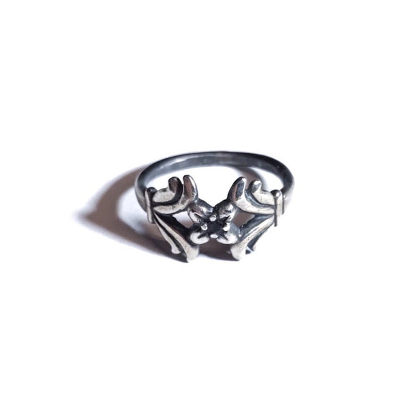 May include: A silver ring featuring a floral design with a black stone at its centre.