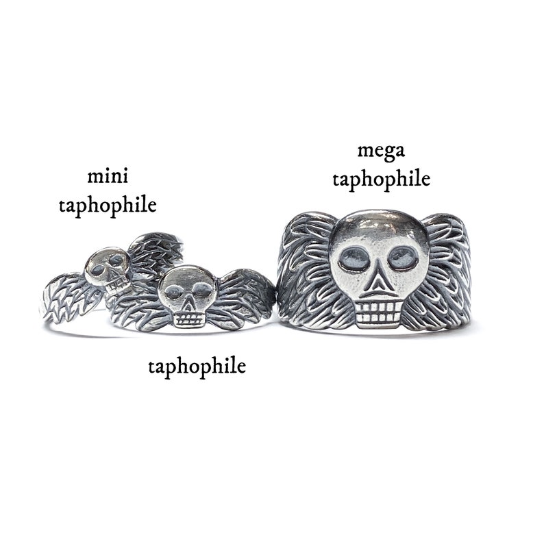 May include: Three silver skull rings with wings, labeled "mini taphophile", "taphophile", and "mega taphophile".