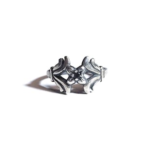 May include: A silver ring featuring a black stone set within a floral design.