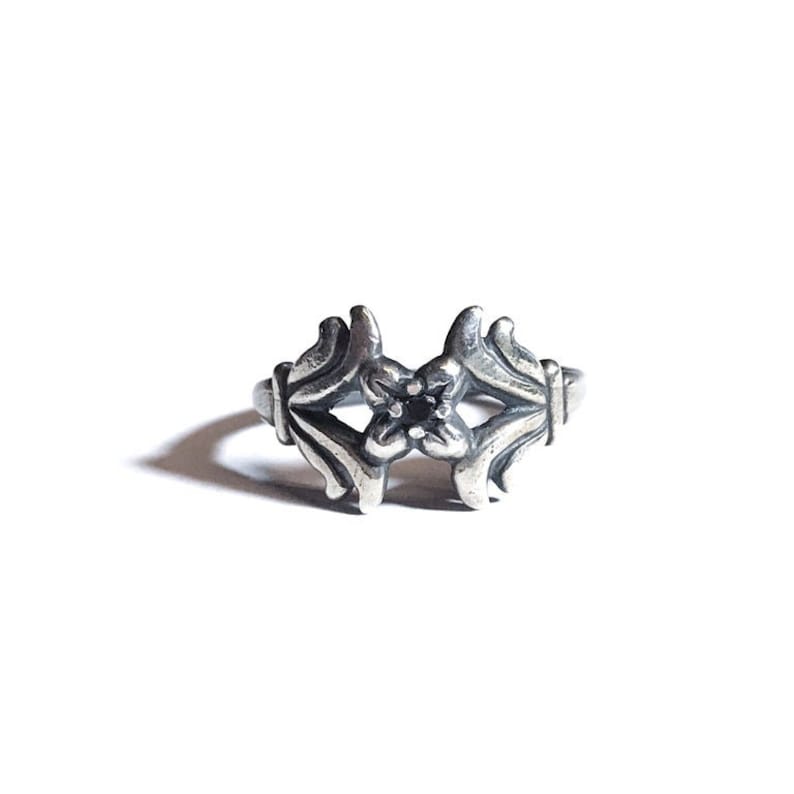 May include: A silver ring featuring a black stone set within a floral design.