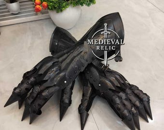 May include: Pair of black metal gauntlets with long, pointed finger extensions. The gauntlets are detailed with rivets and plates, and the Medieval Relic logo is visible. The gloves are designed to resemble claws.