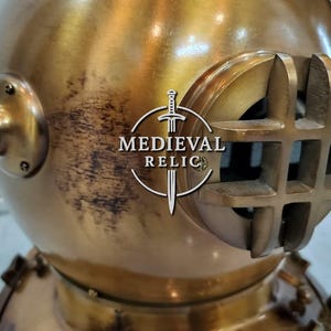 May include: A vintage brass diving helmet with a round body and a large, rectangular viewing window. The helmet has several protruding tubes and fittings, and the text "MEDIEVAL RELIC" is visible on the front.