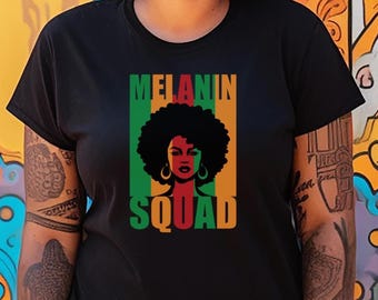 May include: Black t-shirt featuring a graphic of a woman with an afro and the words "MELANIN SQUAD" in green, red, and orange. The design is centered on the shirt, with the text stacked vertically. The woman's face is detailed with gold earrings.