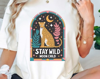 May include: White t-shirt with a graphic of a leopard in a stained glass window with the text "Stay Wild Moon Child".