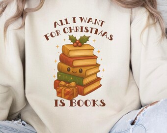 以下が含まれることがあります： 「ALL I WANT FOR CHRISTMAS IS BOOKS」の文字が入ったクリーム色のスウェットシャツ。笑顔の顔、ヒイラギ、包まれたギフトが付いた本の山が描かれています。デザインは茶色、緑、オレンジの色合いを使用しています。