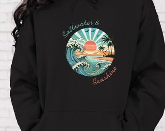 Puede incluir: Sudadera con capucha negra con un gráfico de una puesta de sol sobre olas oceánicas y palmeras. El texto "Saltwater & Sunshine" está escrito en un círculo alrededor del gráfico.