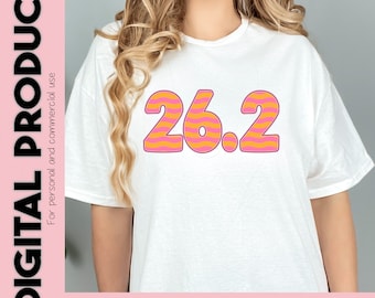 Op de afbeelding: Een wit T-shirt met het nummer 26.2 bedrukt in roze en oranje met een golvend gestreept patroon. De tekst "INCLUDES: SVG PNG JPG FILES" is onderaan de afbeelding gedrukt.