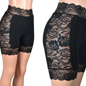 May include: Black biker shorts with black lace trim and panels. The lace panels are on the sides of the shorts and at the bottom hem.