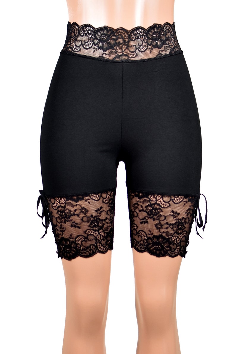 May include: Black biker shorts with a lace trim around the waist and at the bottom of the legs. The lace has a floral pattern.
