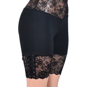May include: Black shorts with a high waist and lace trim. The lace trim is on the waistband and the bottom of the shorts. The shorts have a tie at the side.