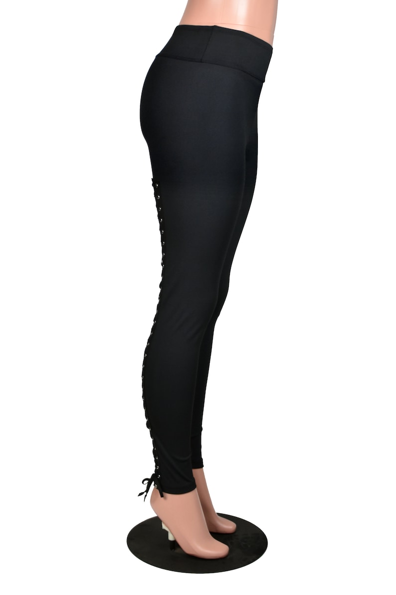 Op de afbeelding: Zwarte leggings met een vetersluiting aan de zijkant van elk been.