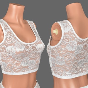 May include: White lace crop top with a scoop neck and sleeveless design. The top is made of delicate lace with a floral pattern.