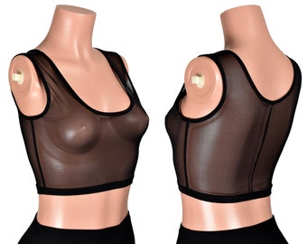 Può includere: Top corto in rete nera con scollo rotondo e senza maniche. Il top è realizzato in tessuto trasparente e ha un bordo nero intorno al collo e alle ascelle.