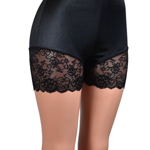 May include: High-waisted black shorts featuring a smooth, satin-like fabric finish on the upper portion and wide, intricate black floral lace trim along the bottom edges of the legs, providing a fitted silhouette.