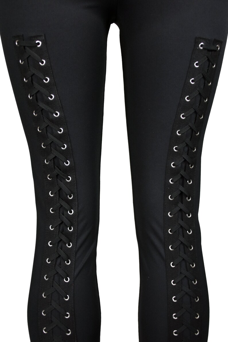 Op de afbeelding: Zwarte leggings met een veterdetail aan de zijkanten. De veters zijn zwart en de oogjes zijn zilver.