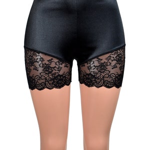 May include: High-waisted black shorts featuring a smooth, satin-like finish on the upper portion and intricate black floral lace panels along the lower leg openings. The garment has a fitted silhouette with a clean, straight waistband.