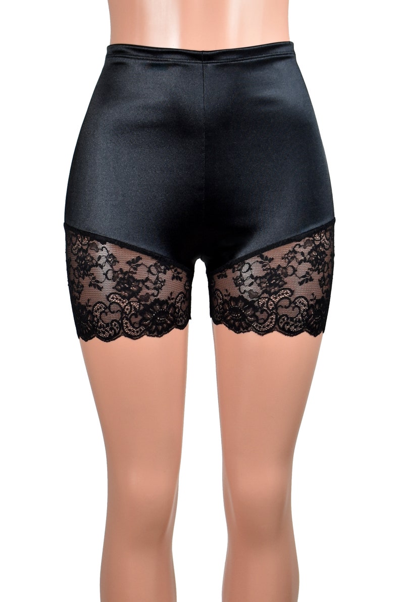 May include: High-waisted black shorts featuring a smooth, satin-like finish on the upper portion and intricate black floral lace panels along the lower leg openings. The garment has a fitted silhouette with a clean, straight waistband.