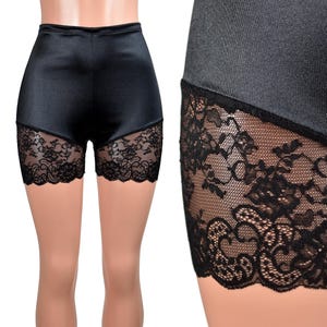 May include: High-waisted black shorts featuring a smooth satin-like finish on the upper portion and wide panels of intricate black floral lace along the lower leg openings. The garment has a fitted silhouette with a clean, straight waistband.