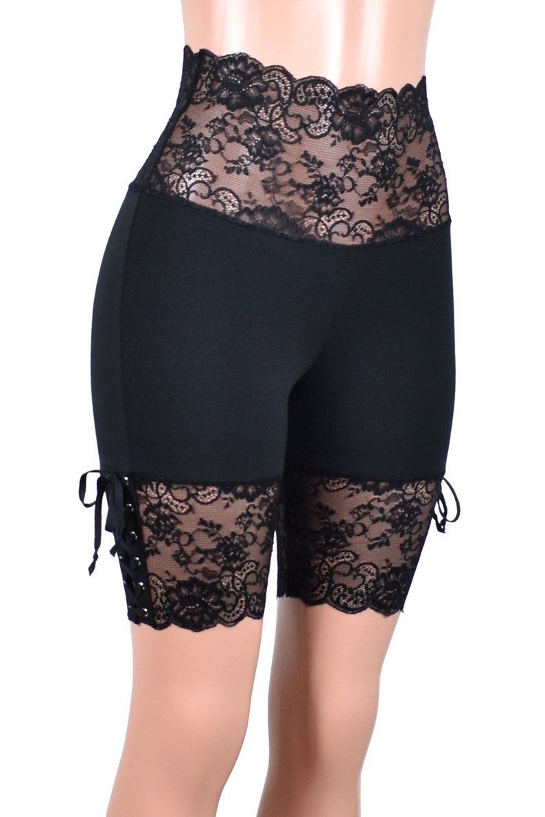 May include: Black biker shorts with lace trim at the waist and legs. The lace trim has a floral pattern and is tied at the sides.