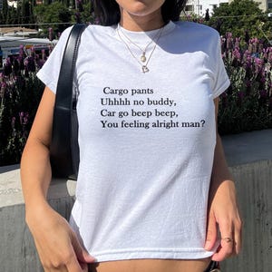 May include: White t-shirt with the text "Cargo pants Uhhhh no buddy, Car go beep beep, You feeling alright man?" printed in black. The shirt is a crew neck style.