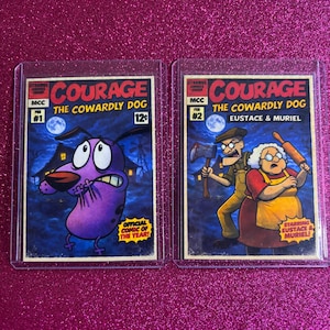 May include: Two Courage the Cowardly Dog comic cards. The first features Courage with the text "Official Comic of the Year!" The second card shows Eustace and Muriel. Both cards are in protective sleeves.