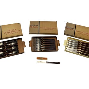 May include: Three vintage Stanley flatware sets in their original boxes and trays. The sets include teaspoons, steak forks, and steak knives. The boxes are tan with black text and the words "Stanley Quality plus" printed on them.