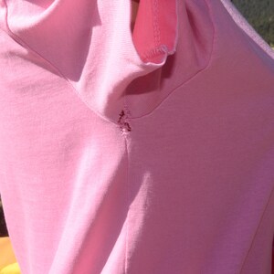 May include: A pink t-shirt with a small tear in the shoulder seam.